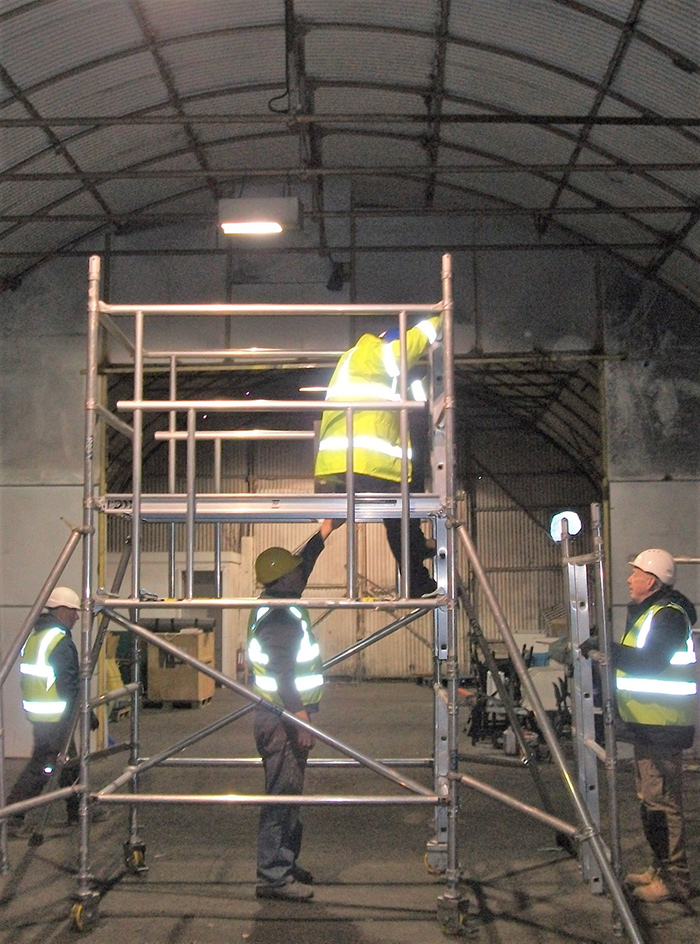 Men in high-vis vests working on a mobile access tower as part of the PASMA course